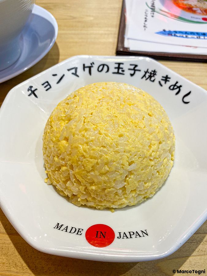 Un piatto di riso all'uovo a forma di cupola servito in un piatto bianco personalizzato presso Ramen Chonmage Osaka Tenrok...