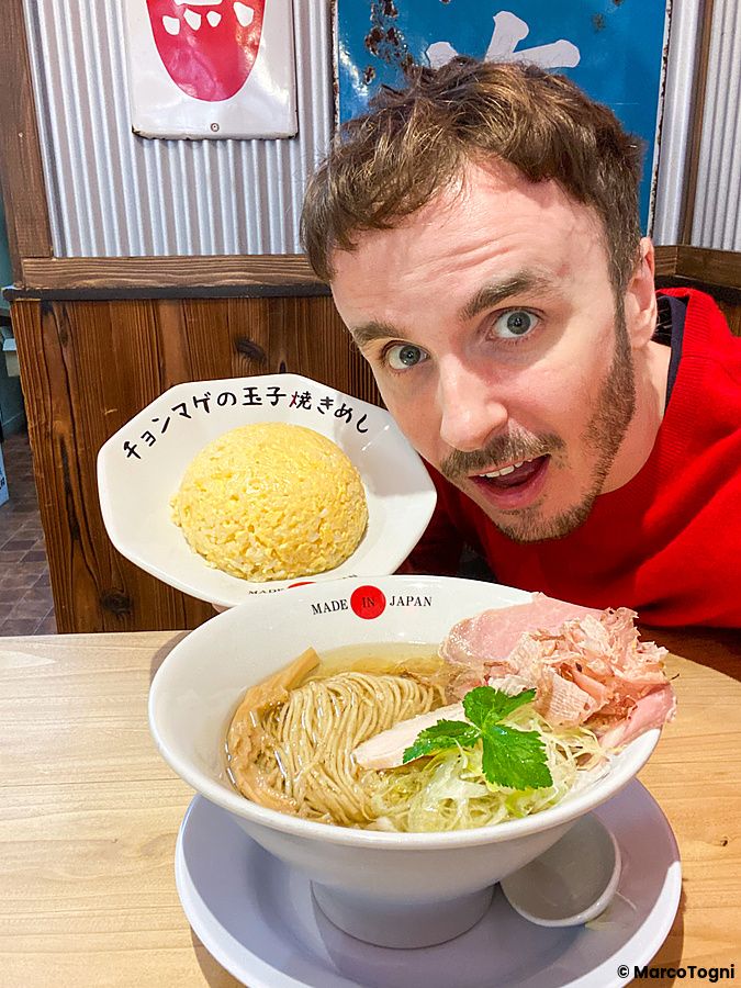 Marco Togni mostra un piatto di riso e una ciotola di ramen presso il ristorante Ramen Chonmage Osaka Tenroku Ten a Osaka.
