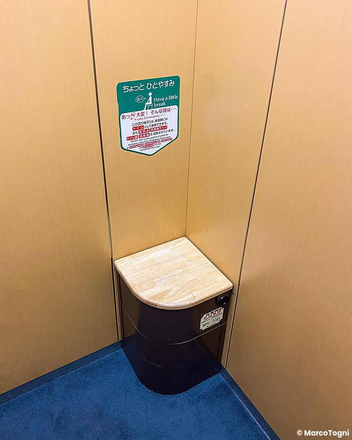 Scatola di emergenza in un ascensore giapponese, con piano in legno e cartelli.