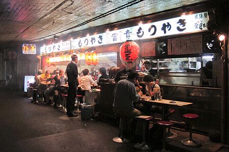 Persone sedute in una izakaya sotto un ponte a Tokyo, Giappone.