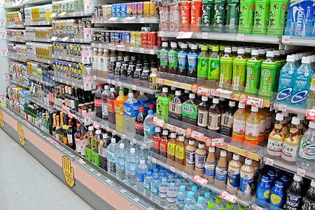 Scaffali di un minimarket in Giappone con numerose bottiglie e lattine di bevande disposte in modo ordinato.