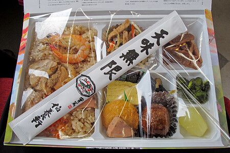 Un ekiben giapponese con varie pietanze in un contenitore suddiviso.