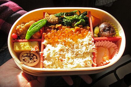 Bento giapponese tenuto da una persona in una stazione ferroviaria.