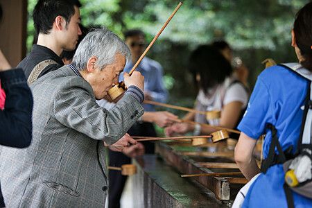 Persone che usano mestoli di legno per raccogliere acqua da una fontana purificatrice.