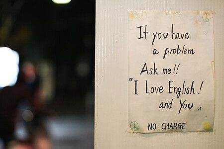 Un cartello scritto a mano affisso all'ingresso di un bar a Golden Gai che offre assistenza in lingua inglese.