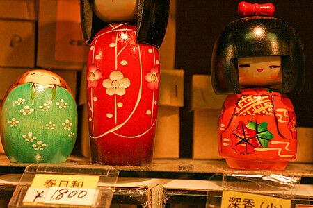 Tre bambole kokeshi giapponesi in mostra su uno scaffale.