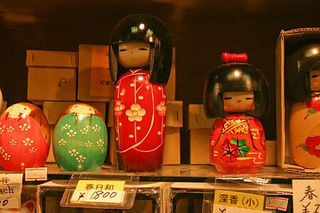 Bambole kokeshi esposte su uno scaffale decorato.