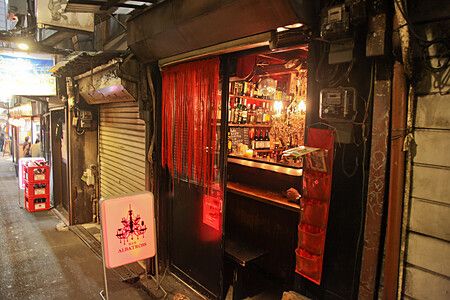 Una piccola izakaya illuminata da luce rossa dentro Omoide Yokocho a Shinjuku.