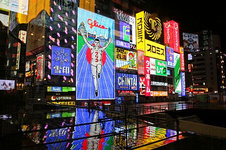 Insegne al neon di Dotonbori a Osaka di notte con riflessi sul canale.
