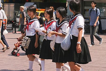 Gruppo di studentesse in uniforme cammina per strada in giappone.