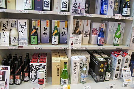 Scaffali di un negozio di Aomori con numerose bottiglie di sakè e shochu locale esposte per la vendita.