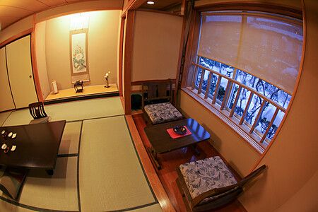 Una camera in stile giapponese con tatami e area salotto presso il ryokan Ichinomatsu di Hakodate vista in inverno.