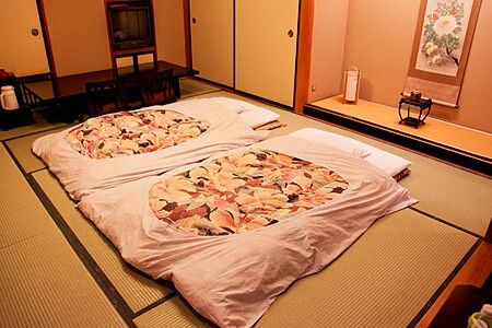 Due futon distesi su un pavimento in tatami all'interno di una stanza tradizionale del ryokan Ichinomatsu a Hakodate.