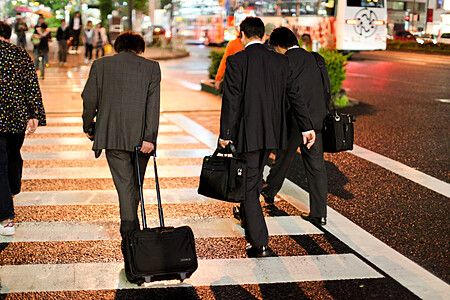 Tre uomini in abiti formali attraversano una strada di notte in Giappone