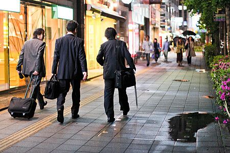 Persone in abiti formali camminano su un marciapiede illuminato in giappone