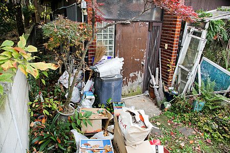 Cortile di una casa abbandonata a Sengawa con rifiuti e scatole.