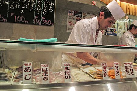 Cuoco giapponese prepara sushi al banco in un ristorante a shinjuku, Giappone.