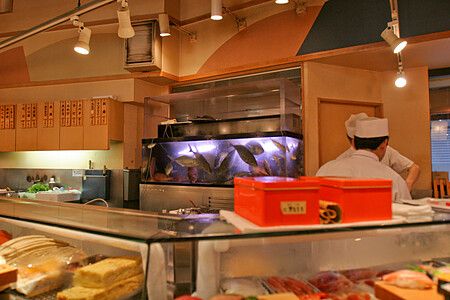 Interno di un sushi bar in Giappone con acquario e cuoco.