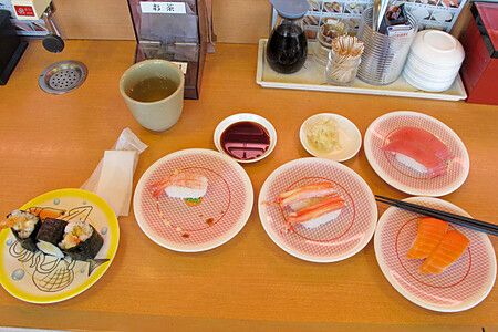 Piatti di sushi e tè verde su un bancone in un ristorante giapponese.