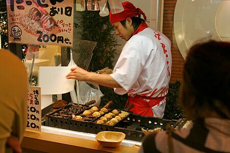Cuoco prepara takoyaki in una bancarella a osaka