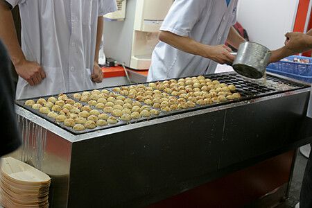 Takoyaki in preparazione su una piastra a Osaka.