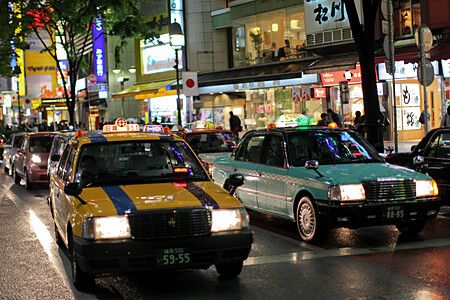 Un taxi notturno giappone circola in una strada illuminata dai neon durante la notte in Giappone.