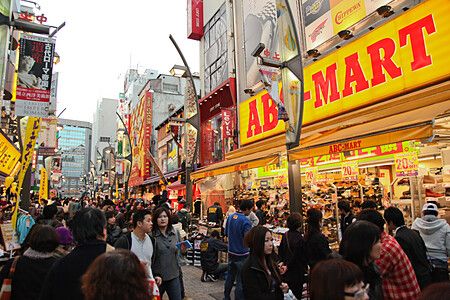 Molte persone camminano lungo la strada affollata di Ameyoko a Ueno, circondata da negozi con insegne gialle e rosse.