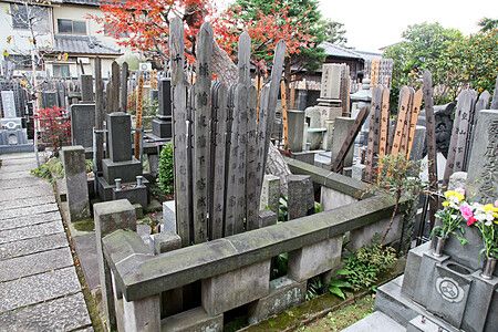 Cimitero tradizionale a Yanaka, Tokyo, con lapidi e alberi autunnali.