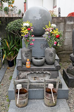 Monumento funebre tradizionale giapponese con fiori e strumenti rituali a Yanaka, Tokyo.