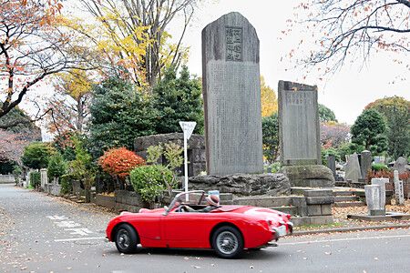 Decappottabile rossa davanti a monumenti in un cimitero a Yanaka, Tokyo.