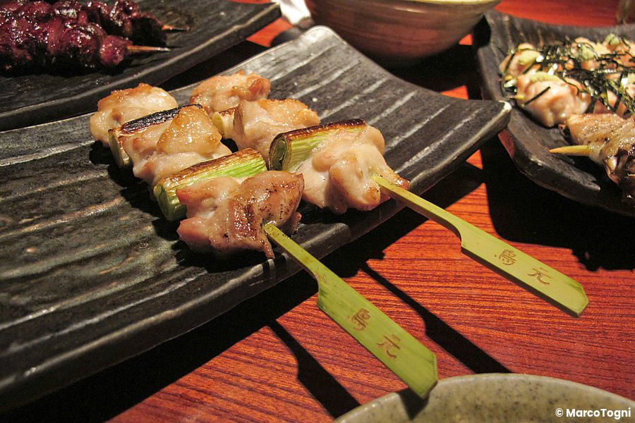 Spiedini di yakitori serviti su piatti in un izakaya giapponese.