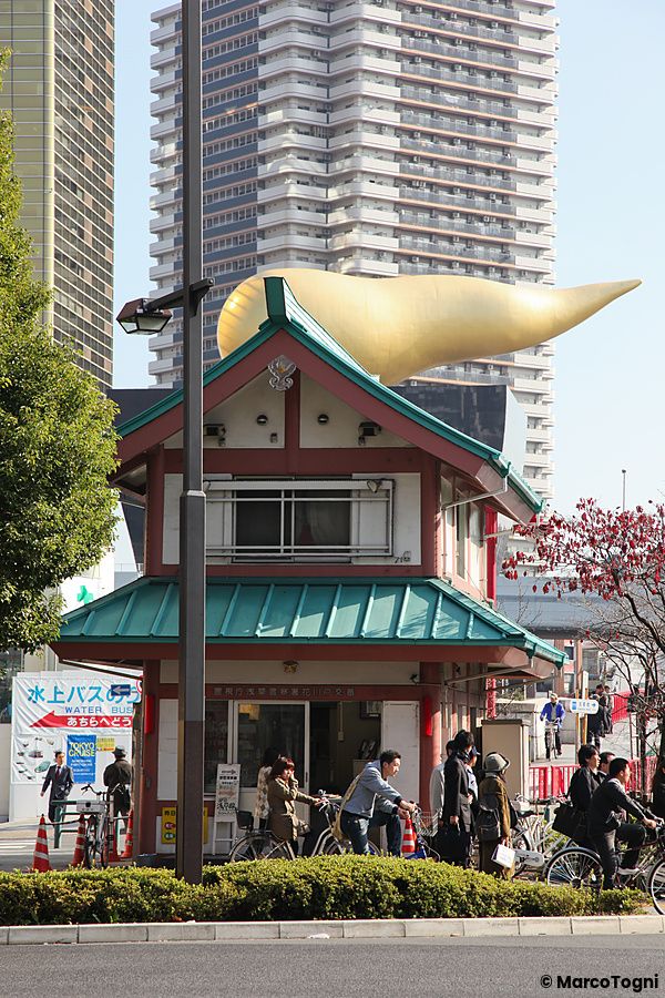 Il piccolo edificio di guardia del koban ad Asakusa si staglia contro un moderno grattacielo con una scultura dorata.