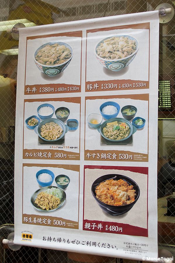 Un menu vetrina di Yoshinoya esposto in Giappone con fotografie di ciotole di riso e set di pietanze.