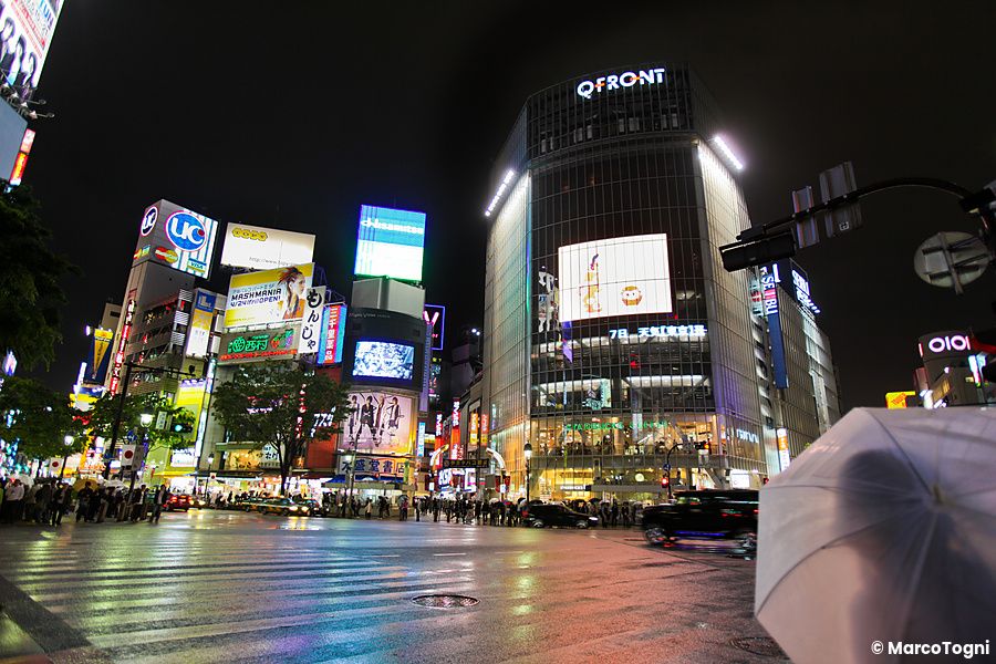 un incrocio illuminato a Shibuya con la pioggia e luci al neon.