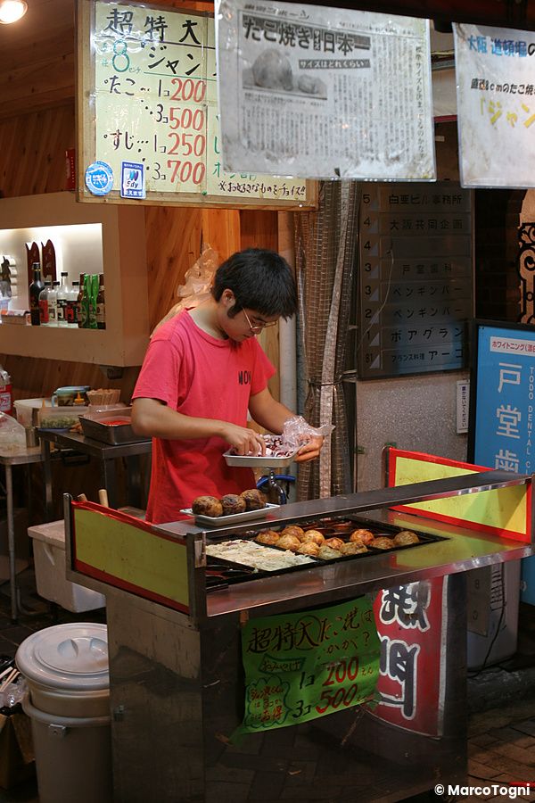 Persona che prepara takoyaki in un chiosco di strada a Osaka
