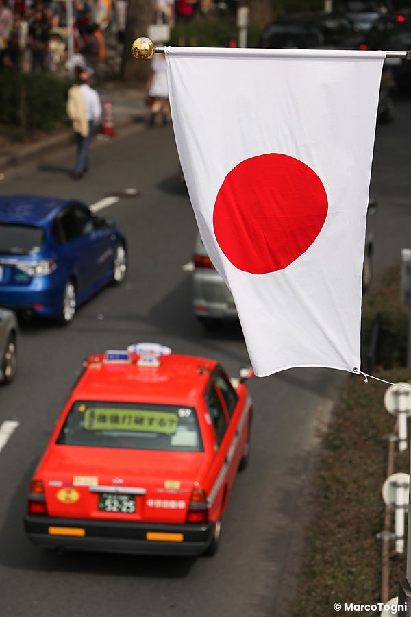 Taxi rosso sotto una bandiera giapponese in una strada trafficata in Giappone.