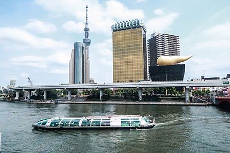 Il battello Himiko naviga sul fiume Sumida a Tokyo con la Tokyo Skytree e l'edificio Asahi in secondo piano.
