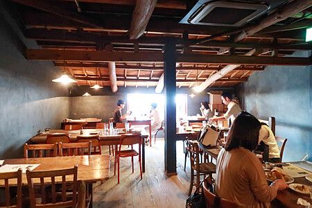 Interno di una caffetteria con persone sedute ai tavoli in un ambiente rustico.