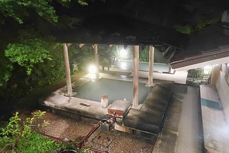 Onsen di notte all'Oku Nikko Hotel Shikisai con luci soffuse e vegetazione.