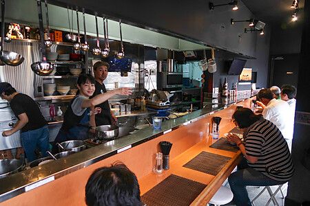 Interno del ristorante Shibasakitei con personale e clienti al bancone vicino alla stazione di Tsutsujigaoka, Tokyo.