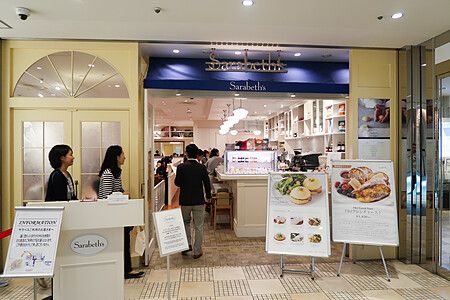 Ingresso del ristorante Sarabeth a Tokyo con due persone dello staff al banco informazioni e un cliente che entra.
