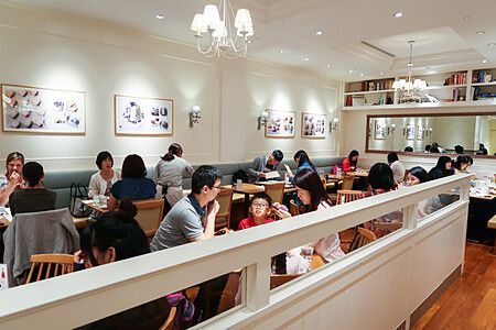 Veduta interna della sala da pranzo del ristorante Sarabeth a Tokyo, affollata di persone sedute ai tavoli.