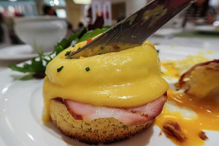 Un coltello taglia un uovo alla Benedict con salsa olandese in un ristorante Sarabeth a Tokyo.
