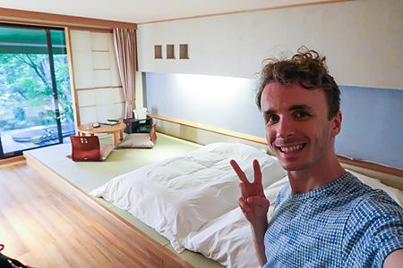Marco Togni sorridente scatta un selfie in una stanza a Oku Nikko Hotel Shikisai con letto futon e pavimento in tatami.