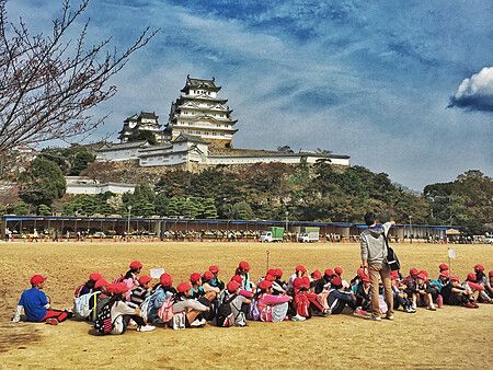 Gruppo di bambini con cappellini rossi davanti al castello di Himeji.