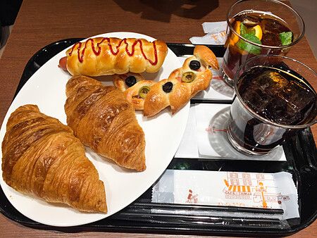 Un vassoio con croissant, pane farcito e due bevande fredde presso la panetteria Donq a Tokyo.