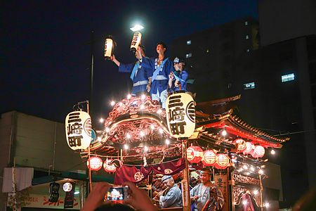 Tre giovani uomini su un carro tradizionale illuminato da lanterne durante l'Hachioji Matsuri a Hachioji.