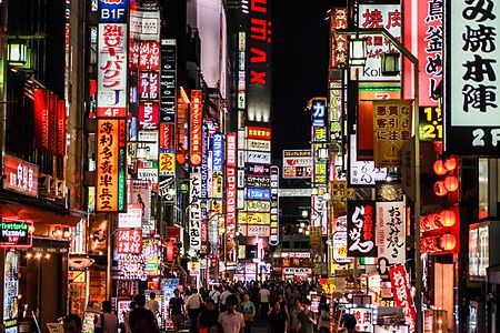 Strada affollata di Kabukicho, Tokyo, illuminata da insegne al neon.