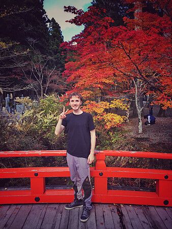 Marco Togni su un ponte rosso con foglie autunnali al tempio Eireiden, Monte Koya.