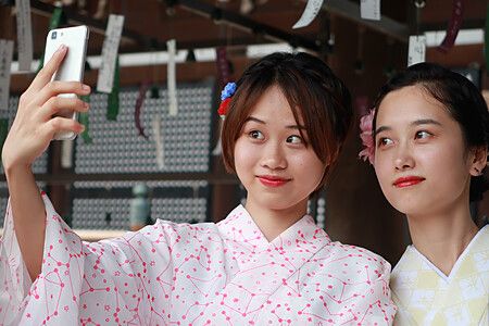 Due persone in kimono scattano un selfie in un contesto tradizionale.